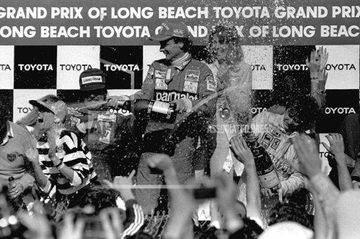 FILE - Two-time Formula 1 world champion Niki Lauda, center, sprays champagne over well wishers around the winner circle at the Grand Prix circuit in Long Beach, Calif., in this April 5, 1982, file photo. Lauda, driving for Team McLaren, won the race, finishing ahead of Team Williams driver Keke Rosberg, left, of Finland, second, and Canadian Gilles Villeneuve, right, who finished third driving for Ferrari. The Grand Prix of Long Beach opens 17 months after the pandemic ended the crown jewel’s streak as one of the longest continuously-running street events in racing. (AP Photo/FIle)