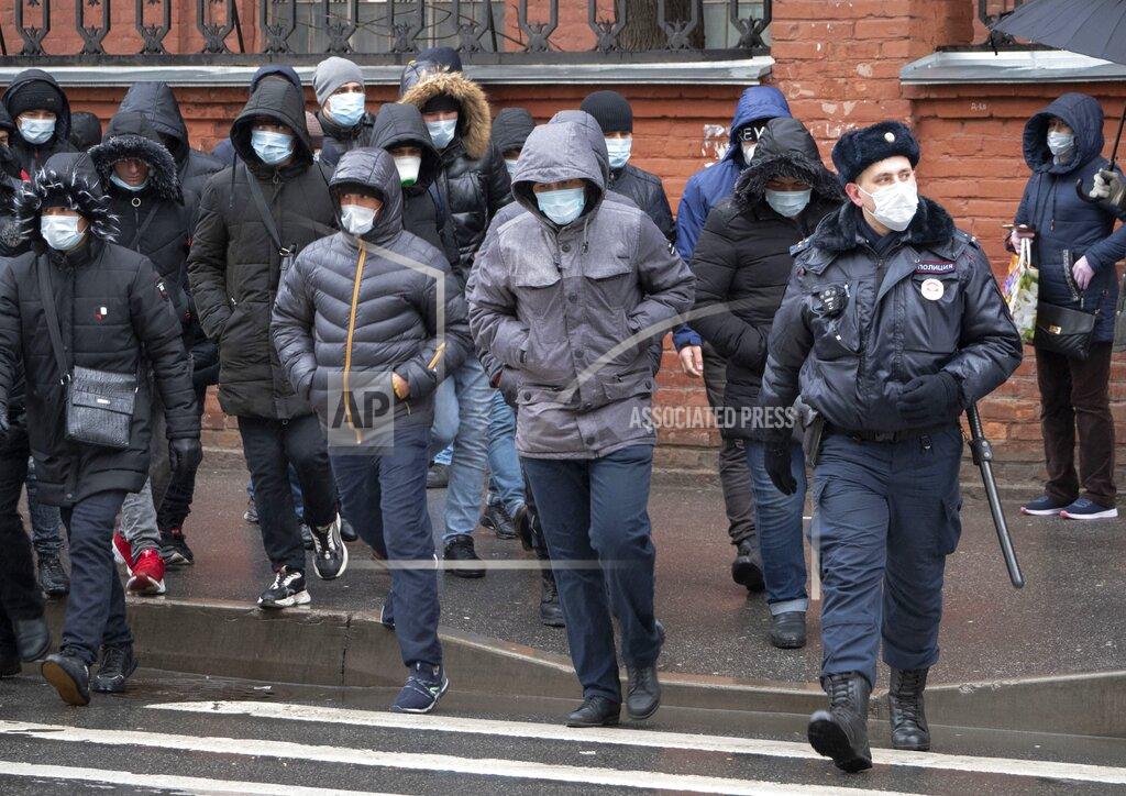 Dmitri Lovetsky A policeman, foreground right, accompanies a group of migrant laborers, who came to renew work permits, to a migration center in St.Petersburg, Russia, Thursday, April 2, 2020. President Vladimir Putin on Thursday ordered most Russians to stay off work until the end of the month as part of a partial industrial shutdown to curb the spread of the coronavirus. The new coronavirus causes mild or moderate symptoms for most people, but for some, especially older adults and people with existing health problems, it can cause more severe illness or death. (AP Photo/Dmitri Lovetsky)