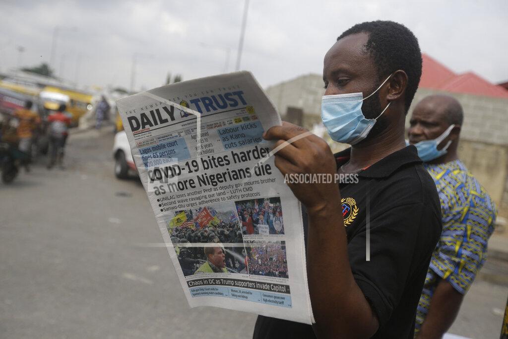 Sunday Alamba A man reads a newspaper reacting to the news of the assault on U.S Congress, on a street in Lagos, Nigeria, Thursday Jan. 7, 2021. News reports show police with gun drawn as protesters try to break into the House Chamber at the U.S. Capitol on Wednesday, Jan. 6, in Washington, USA.(AP Photo/ Sunday Alamba)