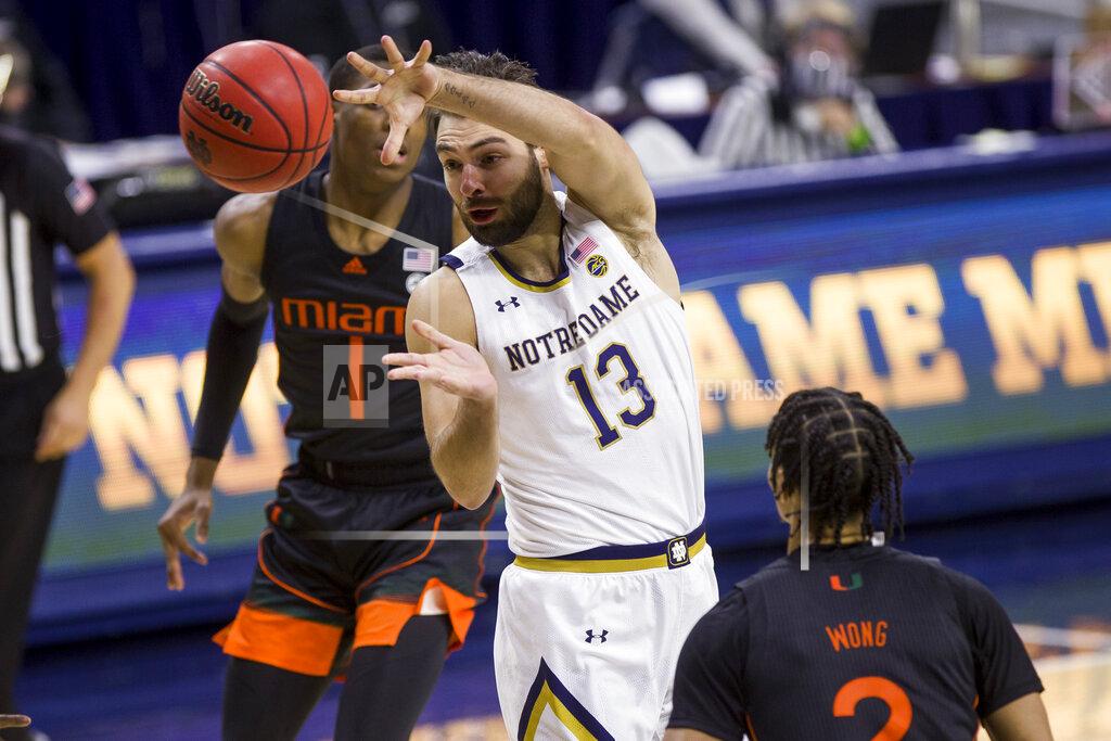 Robert Franklin Notre Dame's Nikola Djogo (13) passes the ball between Miami's Anthony Walker (1) and Isaiah Wong (2) during the second half of an NCAA college basketball game Sunday, Feb. 14, 2021, in South Bend, Ind. Notre Dame won 71-61. (AP Photo/Robert Franklin)