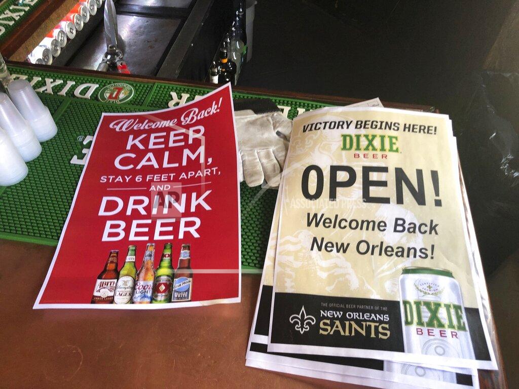 Kevin Mcgill In this Friday, June 12, 2020 photo, stacks of signs for welcoming back patrons sit on the bar at Lafitte's Blacksmith Shop Bar on Bourbon Street in New Orleans. The city is allowing bars to open – with limited capacity and without live music – on Saturday. Bars were among the businesses shut down in mid-March as coronavirus infections increased in New Orleans and Louisiana became a hot spot for the disease. (AP Photo/Kevin McGill)