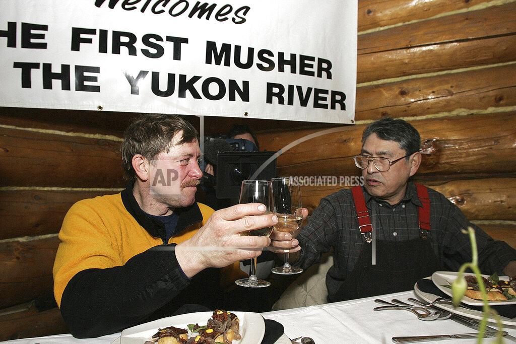 Al Grillo FILE - In this March 10, 2006, file photo, Iditarod veteran and 1975 champion Emmitt Peters, right, toasts Paul Gebhardt, of Kasilof, Alaska, for being the first musher to reach the Yukon River checkpoint of Ruby, Alaska, in the Iditarod Trail Sled Dog Race. Alaska State Troopers confirmed Peters died Thursday, April 2, 2020, at his home in Ruby. (AP Photo/Al Grillo, File)