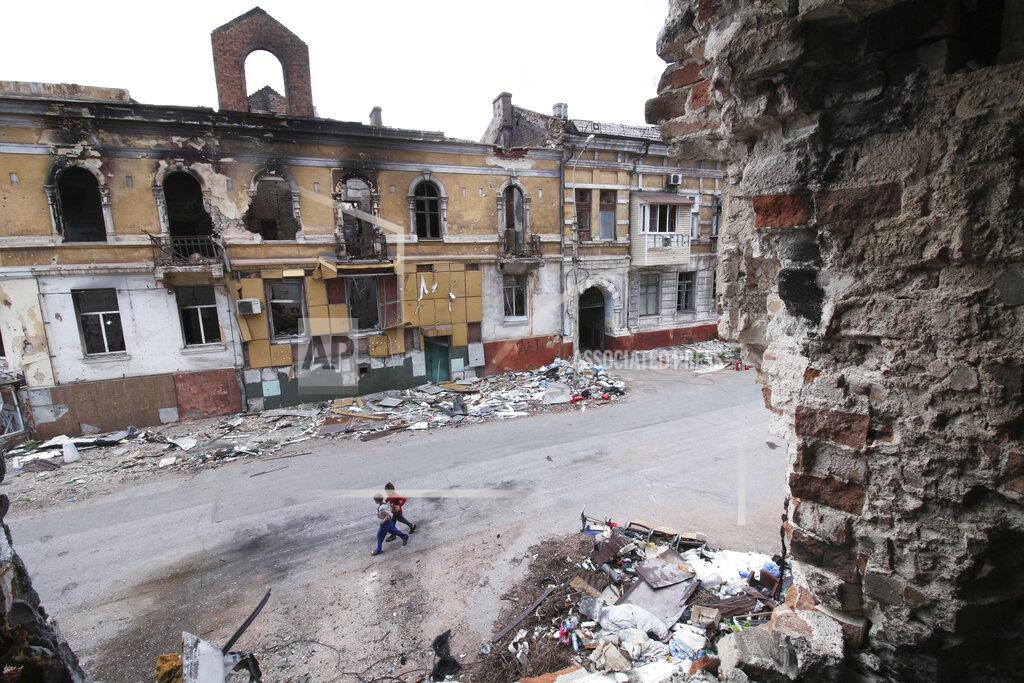 Uncredited Children walk among buildings destroyed during fighting in Mariupol, in territory under the government of the Donetsk People's Republic, eastern Ukraine, Wednesday, May 25, 2022. (AP Photo)