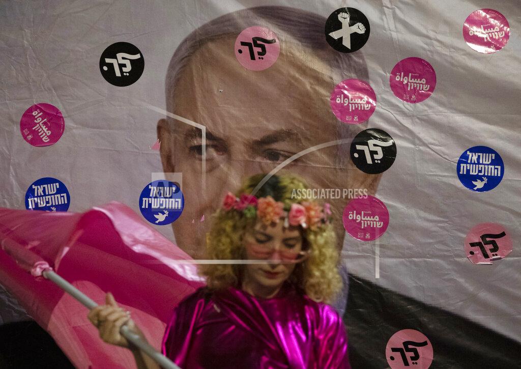 Ariel Schalit An Israeli protester wears pink during a demonstration against Israeli Prime Minister Benjamin Netanyahu outside his official residence in Jerusalem, Saturday, June 12, 2021. If all goes according to plan, Israel will swear in a new government on Sunday, ending Prime Minister Benjamin Netanyahu's record 12-year rule and a political crisis that inflicted four elections on the country in less than two years. Hebrew reads: "You failed"," Israel free" and "Leave". (AP Photo/Ariel Schalit)