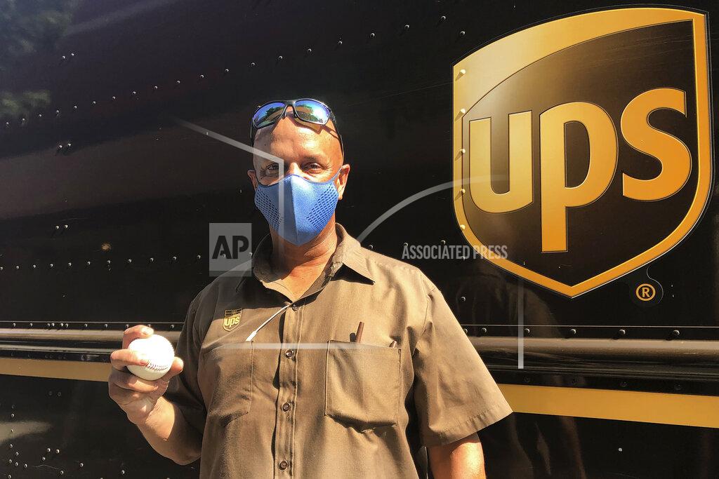 Janie Mccauley UPS driver Derek Reynolds poses with a foul ball gift, Friday, Sept. 18, 2020, in Alameda, Calif. (AP Photo/Janie McCauley)