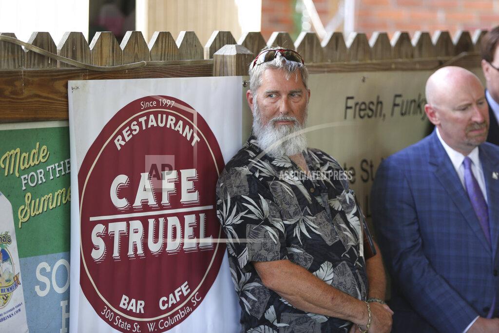 Jeffrey Collins Cafe Strudel owner Trip Turbyfill listens as officials speak during a bill signing ceremony for legislation that prevents people in South Carolina from suing businesses over COVID-19 on Thursday, June 24, 2021 at his restaurant in West Columbia, South Carolina. The bill signing was ceremonial after the General Assembly passed the legislation in April. (AP Photo/Jeffrey Collins)
