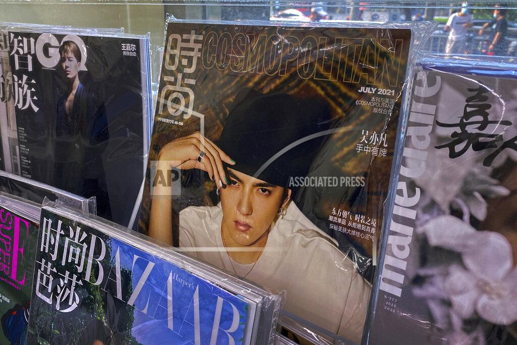 Andy Wong A fashion magazine showing Chinese-Canadian singer Kris Wu, center, on display for sale on a bookshelves at a convenience store in Beijing, Tuesday, July 20, 2021. Kris Wu, has lost endorsement deals with at least 10 brands including Porsche and Louis Vuitton after a teen-ager accused him of having sex with her while she was drunk. (AP Photo/Andy Wong)