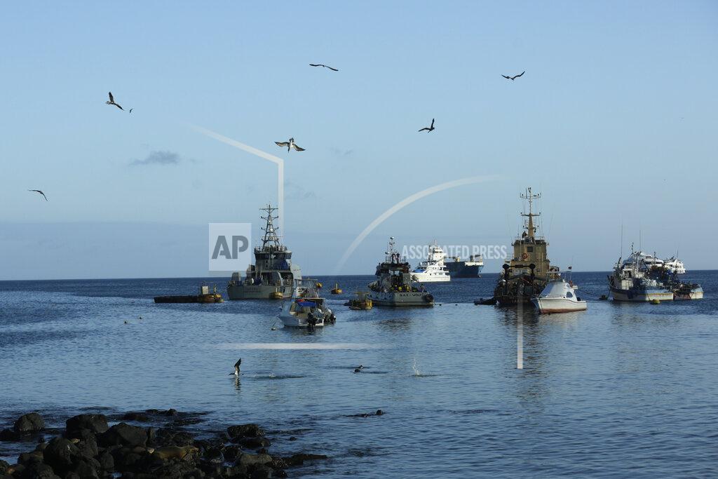 Adrian Vasquez In this May 2, 2020 photo, birds fly over fishing and tourist boats anchored in the bay of San Cristobal, Galapagos Islands, Ecuador. In the past the storied islands have been relatively shielded by what happens 600 miles away on the mainland, but amid the new coronavirus pandemic the island chain's famous isolation is now heightening its hardship. (AP Photo/Adrian Vasquez)