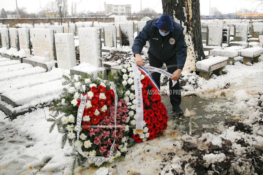 A man adjusts wreaths before the funeral of Iancu Tucarman, at a Jewish cemetery in Bucharest, Romania, Monday, Jan. 11, 2021. Tucarman, one of the last remaining Holocaust survivors in Romania, on was buried after dying from COVID-19 last week at the age of 98. (AP Photo/Vadim Ghirda)