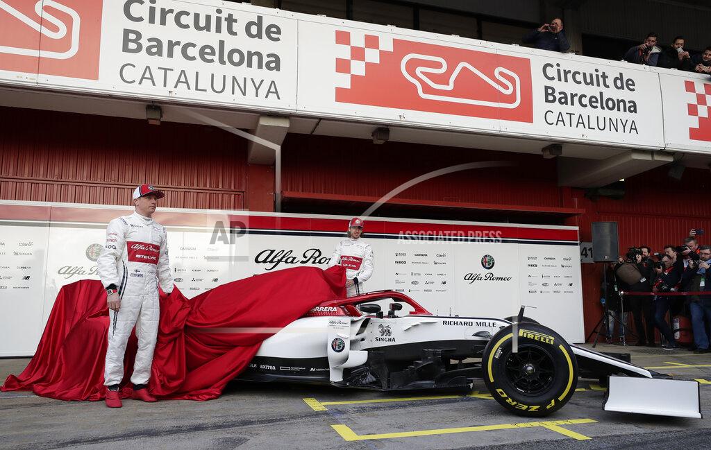 Drivers Kimi Raikkonen of Finland, left, and Antonio Giovinazzi of Italy, center, unveil the new Alfa Romeo F1 car during a presentation of the new livery at the Barcelona Catalunya racetrack in Montmelo, outside Barcelona, Spain, Monday, Feb.18, 2019. (AP Photo/Manu Fernandez)