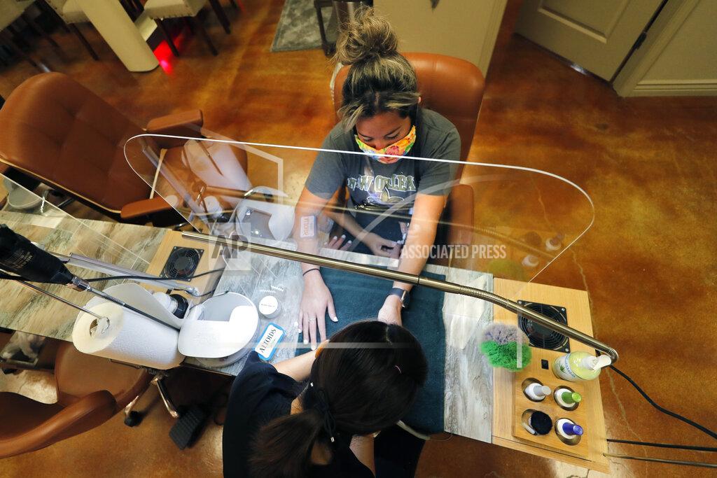 Gerald Herbert Customer Gabi Bustillo gets a manicure through new plexiglass partitions at Luxurie Nail Spa in Harahan, La., Friday, May 15, 2020. Once a hot spot for coronavirus infections, Louisiana is officially easing up Friday on economically devastating business closures and public gathering restrictions that Gov. John Bel Edwards credits with slowing the spread of the virus. With certain limitations — and excluding New Orleans, which doesn't begin easing restrictions until Saturday — Louisiana residents can eat inside restaurants again. (AP Photo/Gerald Herbert)