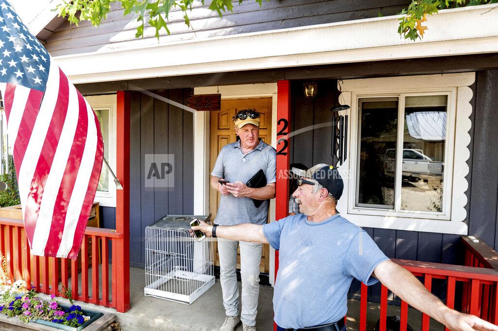 Noah Berger Volunteer firefighter John Hunter, right, describes losing his home and hardware store to the Dixie Fire, Sunday, Sept. 5, 2021, in Quincy, Calif. At left is EmergencyRV.org founder Woody Faircloth, who helped Hunter receive a donated RV. (AP Photo/Noah Berger)