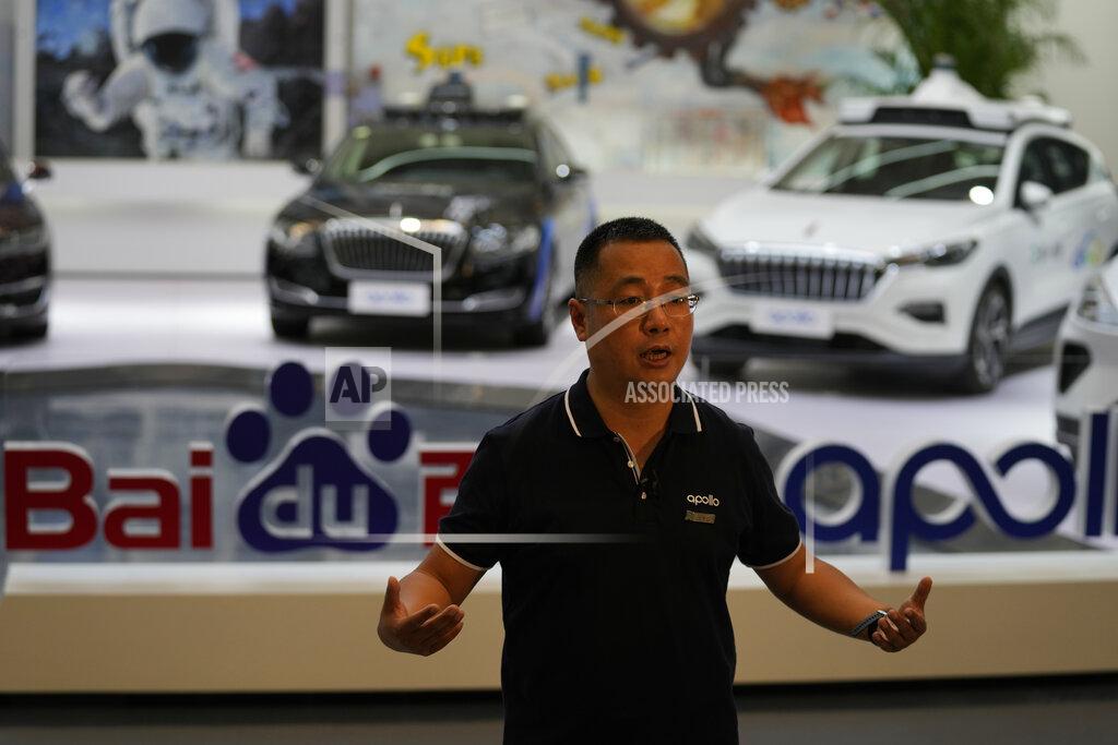 Ng Han Guan Wei Dong, vice president of Baidu's Intelligent Driving Group, speaks near a display showing the various prototypes of the self-driving taxi developed by tech giant Baidu Inc. on June 14, 2022, in Beijing. Baidu Inc. is China's highest-profile competitor in a multibillion-dollar race with Alphabet Inc.'s Waymo and General Motors Co.'s Cruise to create self-driving cars. (AP Photo/Ng Han Guan)