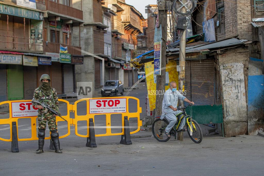 Dar Yasin A Kashmiri cycles past a barricade set up as road blockade as a paramilitary soldier stands guard on the first anniversary of India’s decision to revoke the disputed region’s semi-autonomy, in Srinagar, Indian controlled Kashmir, Wednesday, Aug. 5, 2020. Last year on Aug. 5, India’s Hindu-nationalist-led government of Prime Minister Narendra Modi stripped Jammu-Kashmir of its statehood and divided it into two federally governed territories. Late Tuesday, authorities lifted a curfew in Srinagar but said restrictions on public movement, transport and commercial activities would continue because of the coronavirus pandemic. (AP Photo/ Dar Yasin)