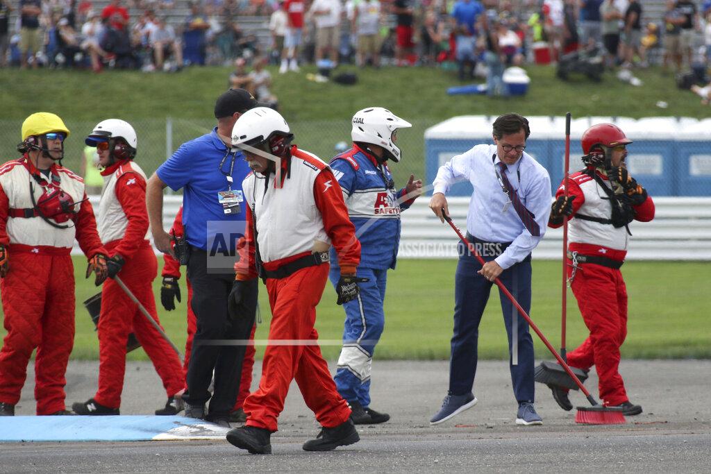 Bob Ruddick Indianapolis Motor Speedway President Doug Boles, second from right, helps crew members clean up the track after a massive crash caused by a piece of curbing during a NASCAR Series auto race at Indianapolis Motor Speedway, Sunday, Aug. 15, 2021, in Indianapolis. (Bob Ruddick/The Indianapolis Star via AP)