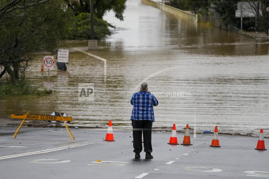 Mark Baker A man takes a photo of flooded street at Windsor on the outskirts of Sydney, Australia, Tuesday, July 5, 2022. Hundreds of homes have been inundated in and around Australia's largest city in a flood emergency that was impacting 50,000 people, officials said Tuesday. (AP Photo/Mark Baker)