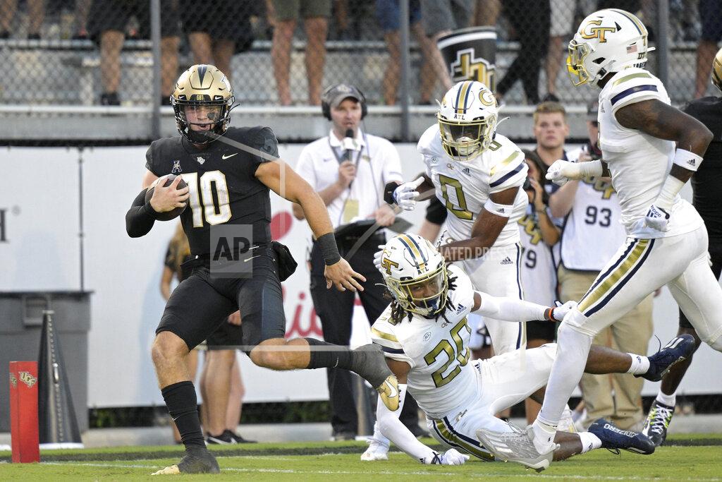 Phelan M. Ebenhack Central Florida quarterback John Rhys Plumlee (10) rushes for a 28-yard touchdown past Georgia Tech defensive backs LaMiles Brooks (20), Myles Sims (0) and Zamari Walton, right, during the second half of an NCAA college football game, Saturday, Sept. 24, 2022, in Orlando, Fla. (AP Photo/Phelan M. Ebenhack)