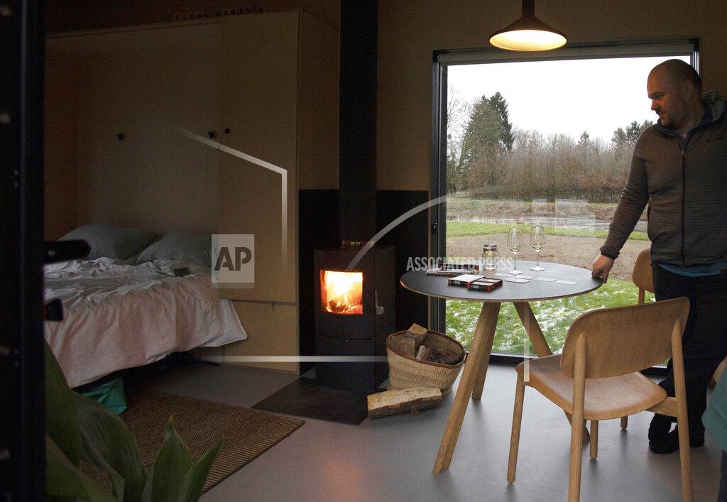 Virginia Mayo Guy De Deyn, enjoys a wood fire as he prepares the table for a game of cards in a Slow Cabin in Elewijt, Belgium, Monday, Feb. 15, 2021. These Slow Cabins, set up the Belgian countryside, are the new way to vacation in pandemic times: in complete solitude and in the middle of nowhere. The wooden cabins are fully sustainable, provided you don't stay in the shower too long and you can live without Wi-Fi. (AP Photo/Virginia Mayo)