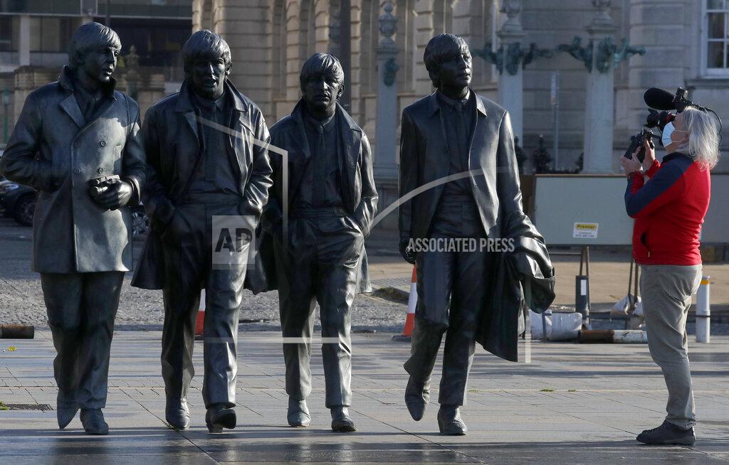 Frank Augstein A video journalist films the Beatles statue in Liverpool, England, Wednesday, Oct. 14, 2020. Liverpool, the English port city that gave the world the Beatles, weathered decades of industrial decline before becoming a celebrated symbol of urban renewal. Now, the coronavirus is putting the city's hard-won revival in jeopardy, and raising tensions between the north of England and the wealthier south. (AP Photo/Frank Augstein)