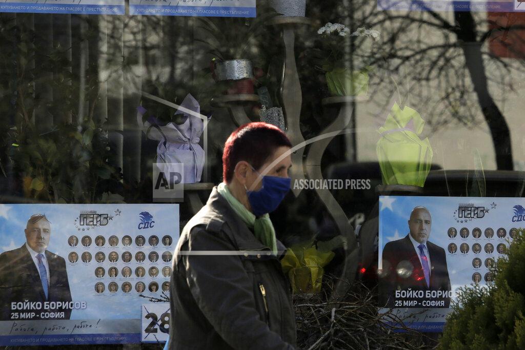 Valentina Petrova A woman passes by a poster depicting Bulgarian prime minister Boyko Borissov, in Sofia, Bulgaria, Wednesday, March 31, 2021. After months of nationwide anti-government protests over corruption, stalled reforms and a stagnating economy in the EU's poorest member state, Bulgarians are gearing up for a parliamentary election overshadowed by a deadly pandemic. (AP Photo/Valentina Petrova)