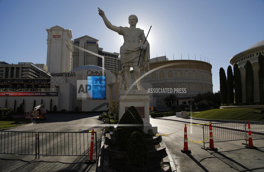 FILE - In this Tuesday, May 26, 2020 file photo gates block an entrance to Caesars Palace hotel and casino along the Las Vegas Strip in Las Vegas. Gambling giants MGM Resorts International and Caesars Entertainment said Wednesday, May 12, 2021, they were opening their Las Vegas Strip gambling floors at 100% capacity with no person-to-person distancing requirement, after state regulatory approval. (AP Photo/John Locher,File)