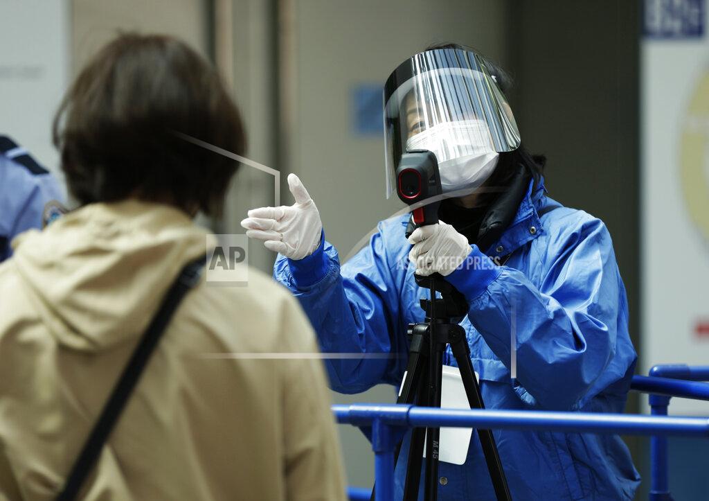 Hiro Komae A worker directs a spectator to a next step to enter the arena after taking the person's temperature during the coronavirus pandemic before the ISU World Team Trophy figure skating competition in Osaka, western Japan on April 15, 2021. The picture is still grim in parts of Europe and Asia as variants of the virus fuel an increase in new cases and the worldwide death toll closes in on 3 million. (AP Photo/Hiro Komae, File)