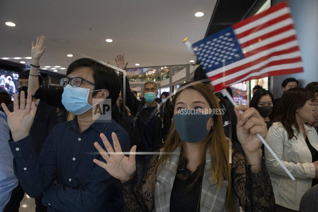 Hongkongers hold up their hands to represent their five demands and a United States flag as they chant