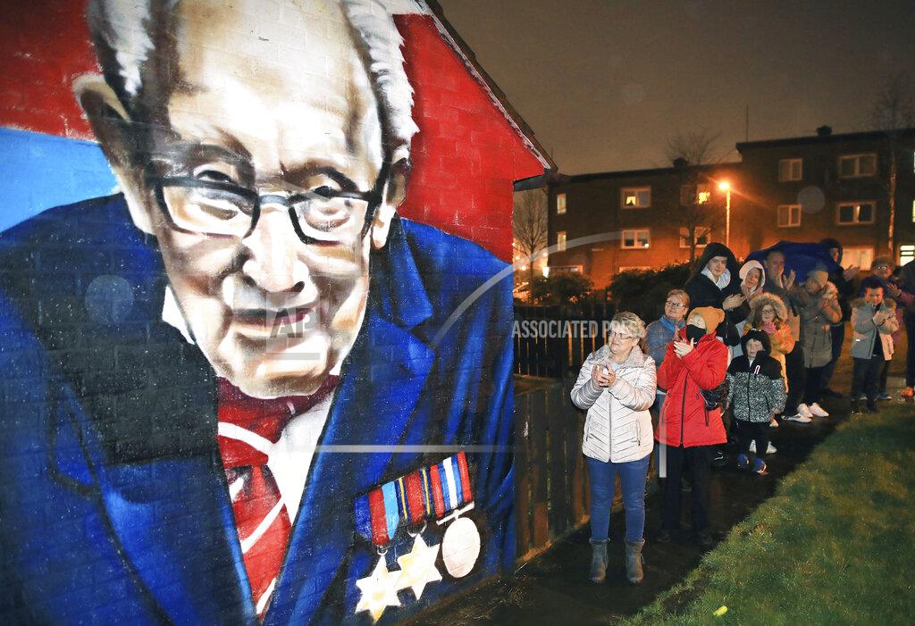 Peter Morrison Local residents join a national clap beside a mural of Captain Sir Tom Moore in East Belfast, Northern Ireland, Wednesday, Feb. 3, 2021. Captain Moore passed away Tuesday after being treated with Covid-19 and was known for his achievements raising millions of pounds for the NHS charity during the Covid-19 pandemic. (AP Photo/Peter Morrison)