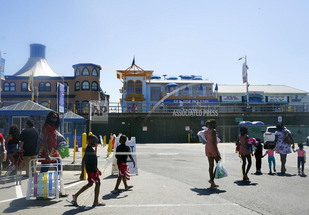 Families walk into the Santa Monica Beach in Santa Monica, Calif., Wednesday, March 31, 2021. Health officials in California and across the country are urging caution because of a troubling rise in new cases of COVID-19, but aquariums and amusement parks are on track to reopen in California anyway. The Pacific Park on the Santa Monica Pier has announced it is preparing to reopen its rides but has only said it expects that to happen sometime after April 1. (AP Photo/Damian Dovarganes)