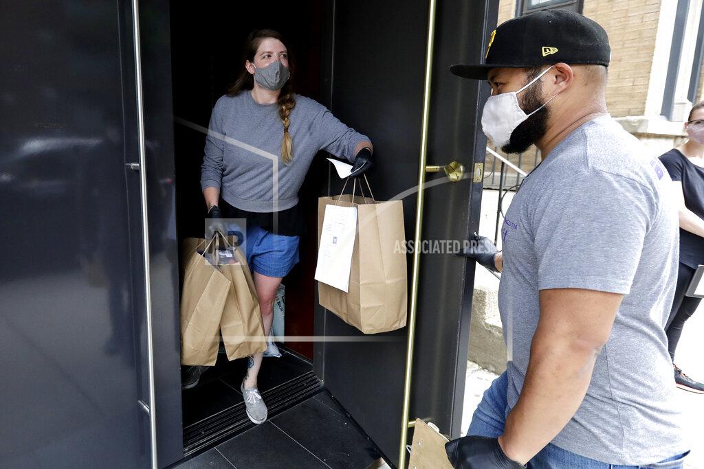 Nam Y. Huh Alinea restaurant manager Rizqi Soeharsono, right, opens the door for restaurant staffer Marry Hammell in Chicago, Saturday, June 20, 2020. Some of the world's best restaurants have had to make a quick pivot to weather the coronavirus. Alinea used to offer an 18-course tasting menu for $365; now it's making carryout meals for $49.94. (AP Photo/Nam Y. Huh)