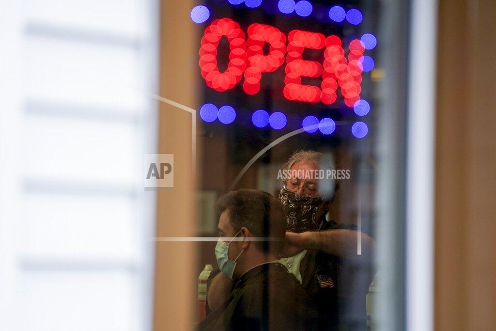 Owner Paul Furrer cuts the hair of Jeff Jones at Rich's Barber Shop on Thursday, May 14, 2020, in Waukesha, Wis. The store re-opened after the Wisconsin Supreme Court struck down Gov. Tony Evers' stay-at-home order Wednesday. (AP Photo/Morry Gash)