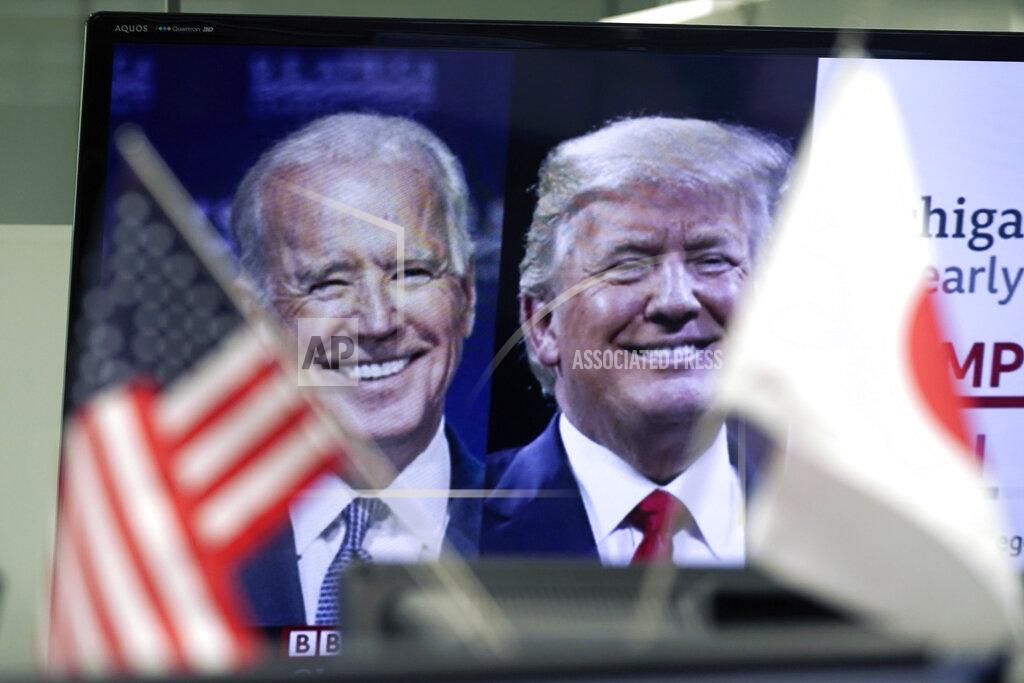 Eugene Hoshiko A Japanese and a U.S. flags are placed in front of a TV monitor showing a news program live broadcasting on the U.S. presidential election between President Donald Trump, right, and former Vice President Joe Biden, left, at a foreign exchange dealing company Wednesday, Nov. 4, 2020, in Tokyo. (AP Photo/Eugene Hoshiko)