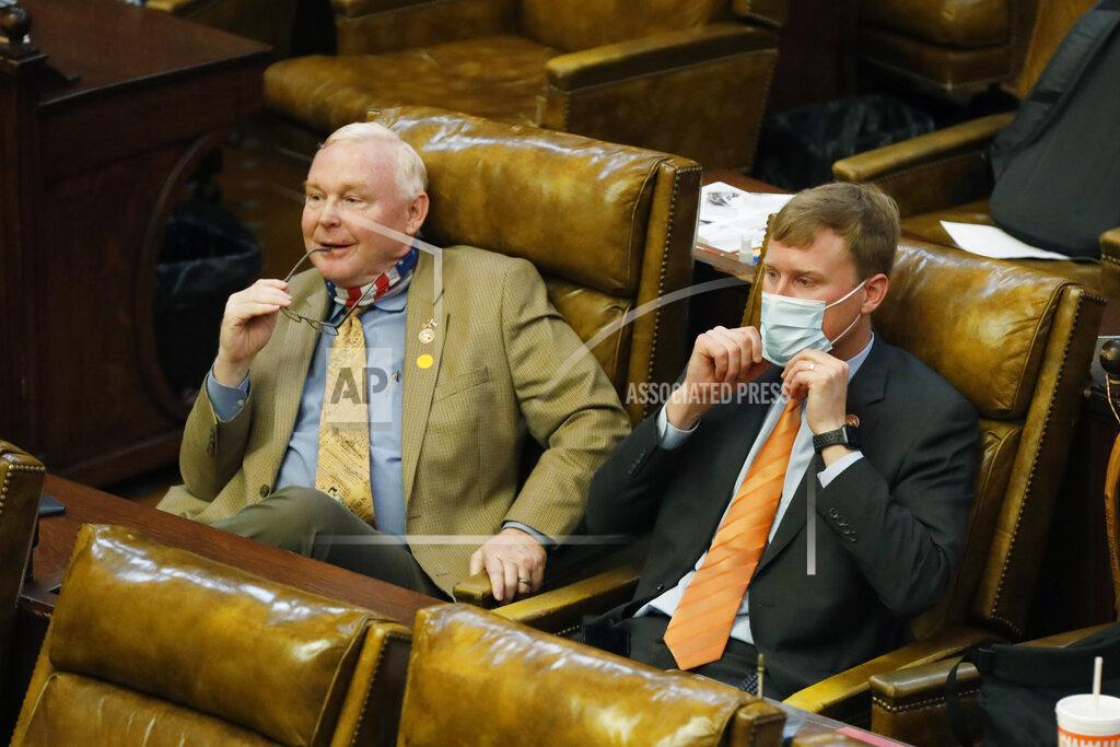 An unmasked Republican Rep. Dana Criswell of Olive Branch, left, sits alongside masked Republican colleague Joel Bomgar, of Madison, Monday, Aug. 10, 2020, as they listen to House Education Committee chairman Richard Beckett, unseen, explain the partial veto of the education budget bill in July by Gov. Tate Reeves, at the Capitol in Jackson, Miss. The House voted 109-7 to override Reeves's veto of the education bill, (AP Photo/Rogelio V. Solis)