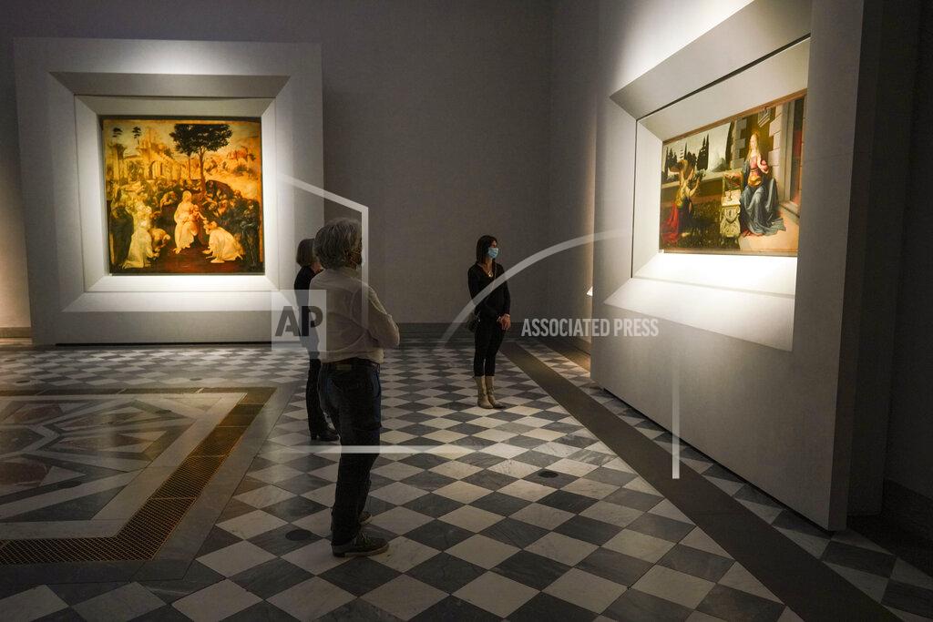 Andrew Medichini Journalists admire 15th century paintings "Annunciation" right, and "Adoration of the Magi" by Leonardo Da Vinci, during a press tour of the Uffizi museum on the day off its reopening, in Florence, Wednesday, June 3, 2020. The Uffizi museum reopened to the public after over two months of closure due to coronavirus restrictions. (AP Photo/Andrew Medichini)