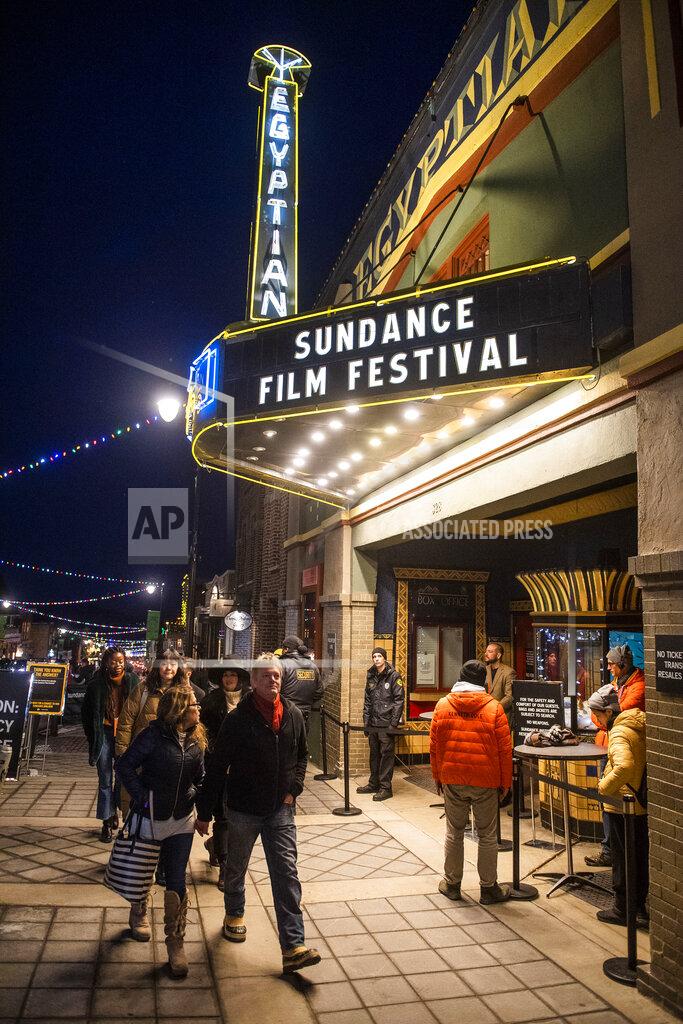 FILE - In this Jan. 28, 2020 file photo, people walk by the the Egyptian Theatre promoting the 2020 Sundance Film Festival in Park City, Utah. Festival organizers said selections from next year’s edition will also play in at least 20 other cities, radically enlarging Sundance’s scope and potentially connecting it more deeply with local communities. (Photo by Arthur Mola/Invision/AP, File)