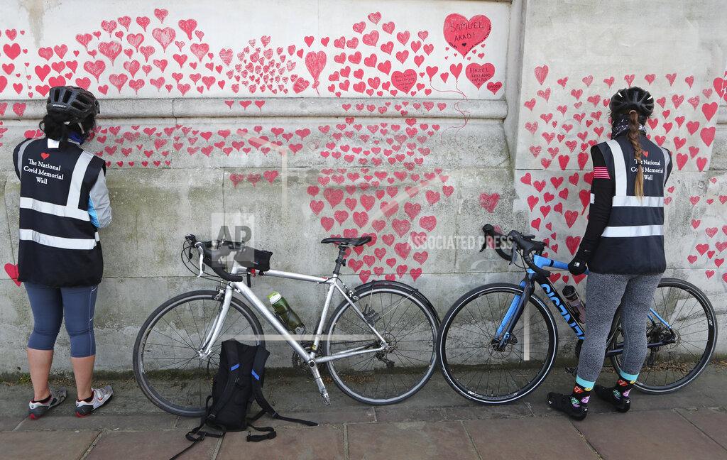 Tony Hicks Women draw hearts on the 'The National COVID Memorial Wall' on the south bank of the Thames in front of St. Thomas' hospital and opposite the House of Parliament in London, Sunday April 4, 2021. Hearts are being drawn onto the wall in memory of the many thousands of people who have died in the UK from coronavirus, with organizers hoping to reach their target of 150,000 hearts by the middle of next week. (AP Photo/Tony Hicks)