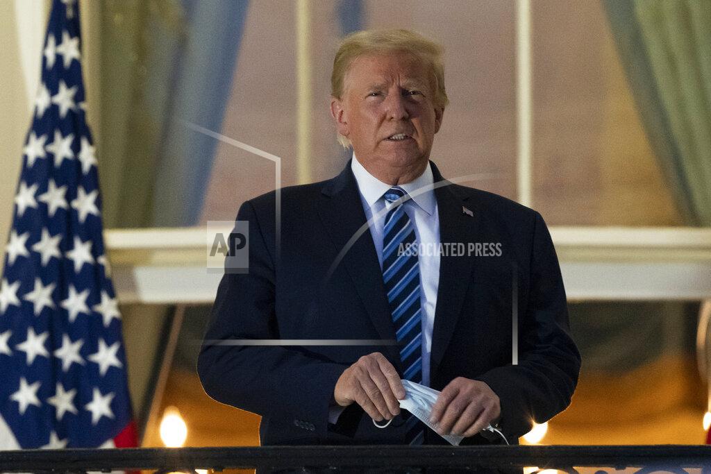Alex Brandon FILE - In this Monday, Oct. 5, 2020 file photo, President Donald Trump removes his mask as he stands on the Blue Room Balcony upon returning to the White House in Washington, after leaving Walter Reed National Military Medical Center, in Bethesda, Md. Trump announced he tested positive for COVID-19 on Oct. 2. (AP Photo/Alex Brandon)