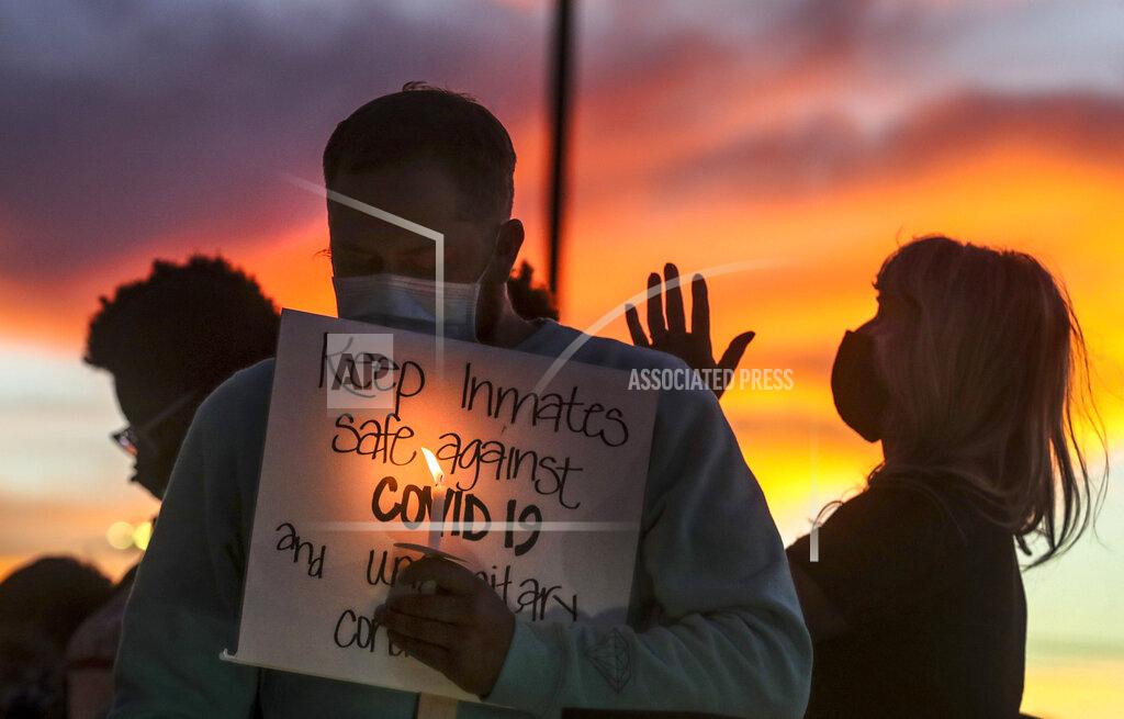 Steve Griffin FILE - In this Oct. 13, 2020, file photo, family members of inmates incarcerated in the Utah Department of Corrections' prison system hold candles and say a prayer following a rally outside the Department of Corrections office in Draper, Utah. One in five state and federal prisoners in the United States has tested positive for the coronavirus, a rate more than four times higher than the general population. In some states, more than half of prisoners have been infected, according to data collected by The Associated Press and The Marshall Project. (Steve Griffin/The Deseret News via AP, File)