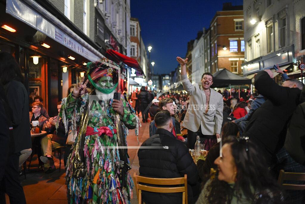 People sit at setup tables outside pubs in Soho, in London, on the day some of England's third coronavirus lockdown restrictions were eased by the British government, Monday, April 12, 2021. Pubs, shops and hairdressers have opened as lockdown restrictions are eased Monday. (AP Photo/Alberto Pezzali)