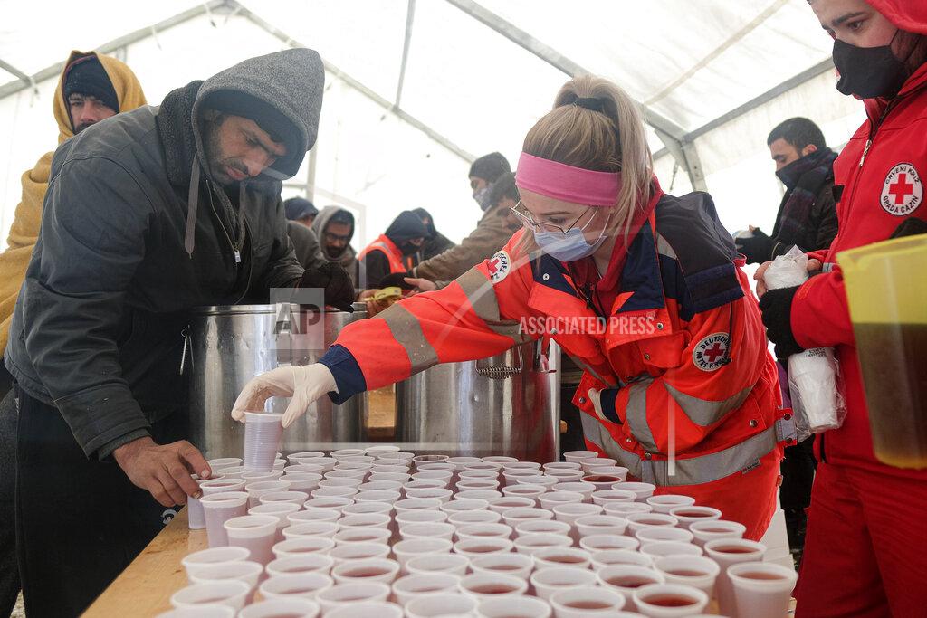 Kemal Softic Migrants wait in a line to get food and warm beverages, at the Lipa camp, outside Bihac, Bosnia, Monday, Jan. 11, 2021. Aid workers say migrants staying at a camp in northwestern Bosnia have complained or respiratory and skin diseases after spending days in make-shift tents and containers amid freezing weather and snow blizzards. Most of the hundreds of migrants at the Lipa facility near Bosnia's border with Croatia on Monday have been accommodated in heated military tents following days of uncertainty after a fire gutted most of the camp on Dec. 23. (AP Photo/Kemal Softic)