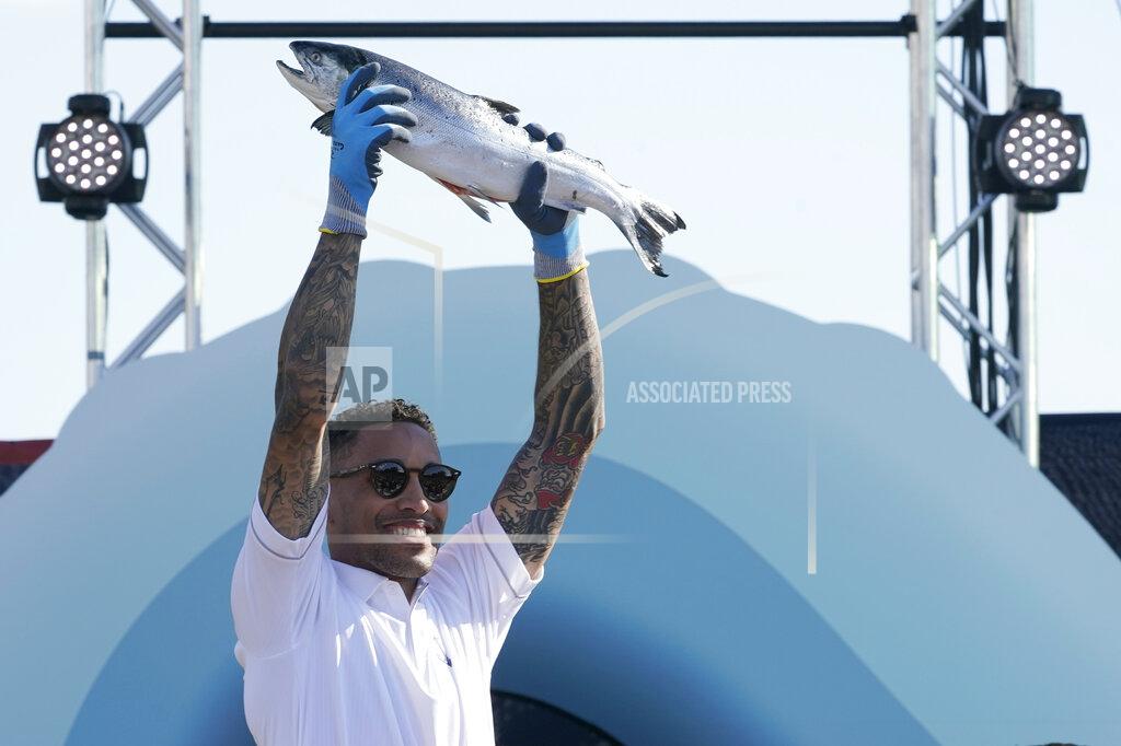 Ted S. Warren Seattle Kraken NHL hockey broadcaster JT Brown holds up a fish after he caught it Wednesday, July 21, 2021, during the Seattle Kraken's NHL hockey expansion draft event in Seattle. (AP Photo/Ted S. Warren)