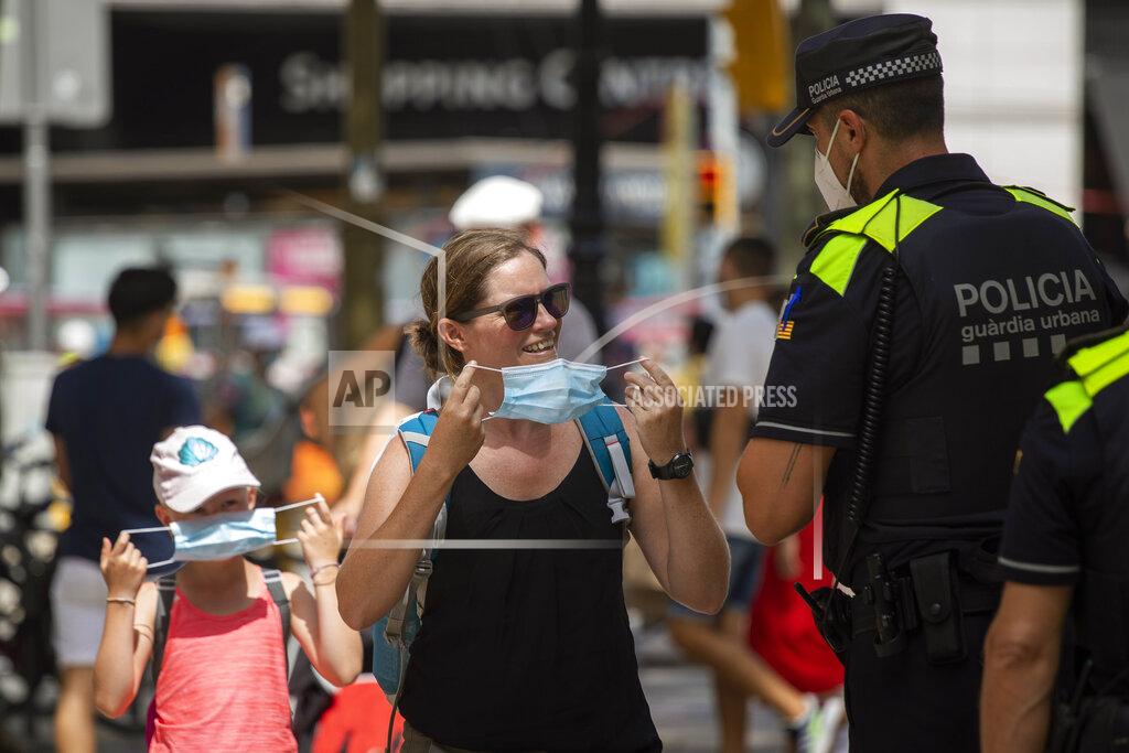 Emilio Morenatti Catalonian police officers ask at a woman to wear a face mask, in Las Ramblas of Barcelona, Spain, Thursday, July 9, 2020. Authorities in northeast Spain will start fining individuals who do not wear face masks 100 euros ($113) as of Thursday when their use becomes obligatory in Barcelona and the surrounding Catalonia region. (AP Photo/Emilio Morenatti)