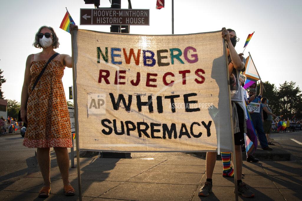 Jozie Donaghey Cherice Boch, left, and her son Espen take part in a protest on Aug. 24 2021, in Newberg, Ore., against a new school policy that bans Black Lives Matter and Pride flags across Newberg School District facilities. The policy has prompted a torrent of recriminations and threats to boycott the town and its businesses. (Jozie Donaghey/The Oregonian via AP)