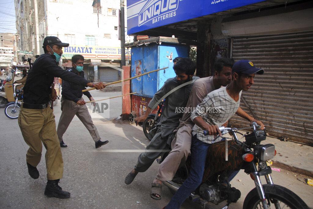 FILE - In this Monday, April 13, 2020 file photo, police officers try to restrict people from defying the nation-wide lockdown to curb the spread of the coronavirus, in Hyderabad, Pakistan. Wealthier Western countries are considering how to ease lockdown restrictions and start taking gradual steps toward reviving business and daily life. But many developing countries, particularly in the Middle East and Africa, can hardly afford the luxury of any misstep. (AP Photo/Pervez Masih, File)