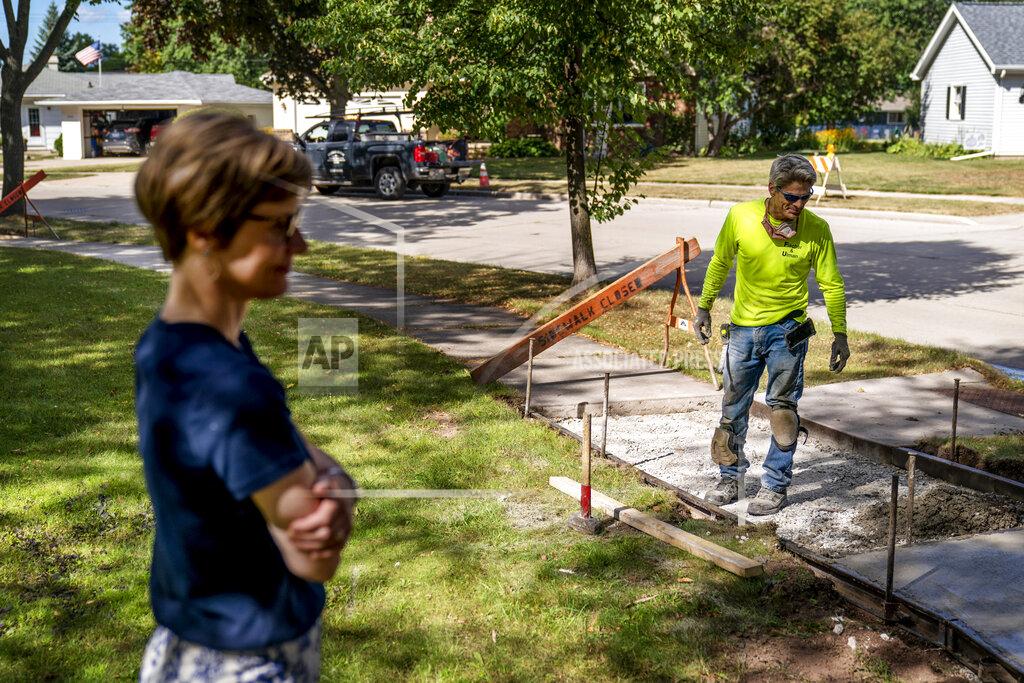 David Goldman Trisha Kostelny, left, who runs Fischer Ulman Construction with her husband, John, right, looks over their sidewalk concrete project in Appleton, Wis., Aug. 18, 2020. The couple are struggling to find workers. The President Donald Trump administration argues the problem is that the government has been too generous with laid-off workers. But to Trisha Kostelny, the problem is that workers need even more help from the government. (AP Photo/David Goldman)