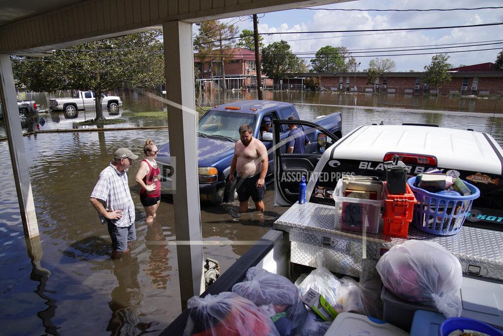 John Locher People stand in floodwaters while salvaging items from their flood-damaged home in the aftermath of Hurricane Ida, Wednesday, Sept. 1, 2021, in Jean Lafitte, La. Louisiana residents still reeling from flooding and damage caused by Hurricane Ida scrambled Wednesday for food, gas, water and relief from the sweltering heat as thousands of line workers toiled to restore electricity and officials vowed to set up more sites where people could get free meals and cool off. (AP Photo/John Locher)