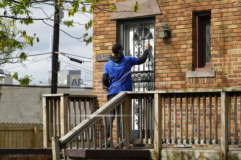 Paul Sancya Sirgregory Allen knocks on a door before leaving a flyer on a home in Detroit, Tuesday, May 4, 2021. Officials are walking door-to-door to encourage residents of the majority Black city to get vaccinated against COVID-19 as the city's immunization rate lags well behind the rest of Michigan and the United States. (AP Photo/Paul Sancya)