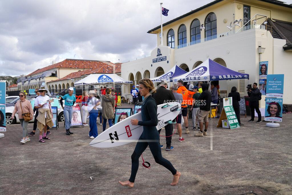 Mark Baker A surfer runs past a polling booth in Sydney, Australia, Saturday, May 21, 2022. Australians go to the polls Saturday following a six-week election campaign that has focused on pandemic-fueled inflation, climate change and fears of a Chinese military outpost being established less than 1,200 miles off Australia's shore.(AP Photo/Mark Baker)