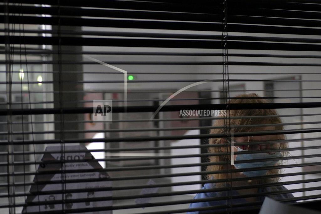 Thibault Camus A patient looks through metal shutters in the Rouvray psychiatric hospital, in Rouen, western France, Wednesday, Nov. 25, 2020. Lockdowns that France has used to fight the coronavirus have come at considerable cost to mental health. Surveying points to a surge of depression most acute among people without work, in financial hardship and young adults. (AP Photo/Thibault Camus)