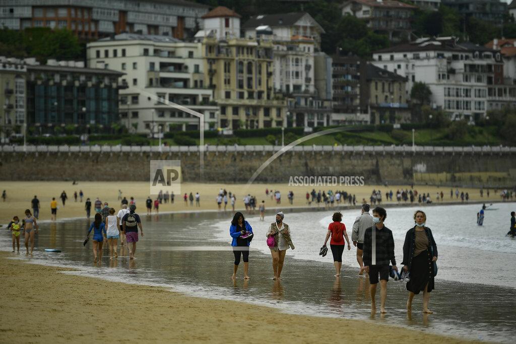 Alvaro Barrientos People walk along La Concha beach, after lockdown restrictions were lifted, in San Sebastian, northern Spain, Sunday, May 9, 2021. Impromptu street celebrations erupted across Spain as the clock struck midnight on Saturday, when a six-month-long national state of emergency to contain the spread of coronavirus ended and many nighttime curfews were lifted. (AP Photo/Alvaro Barrientos)